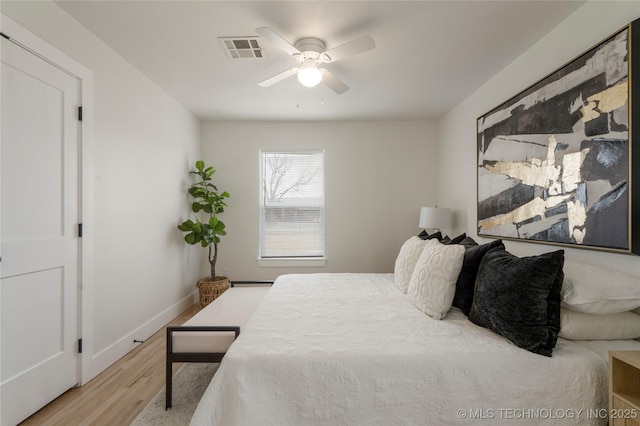 bedroom featuring a ceiling fan, visible vents, baseboards, and wood finished floors