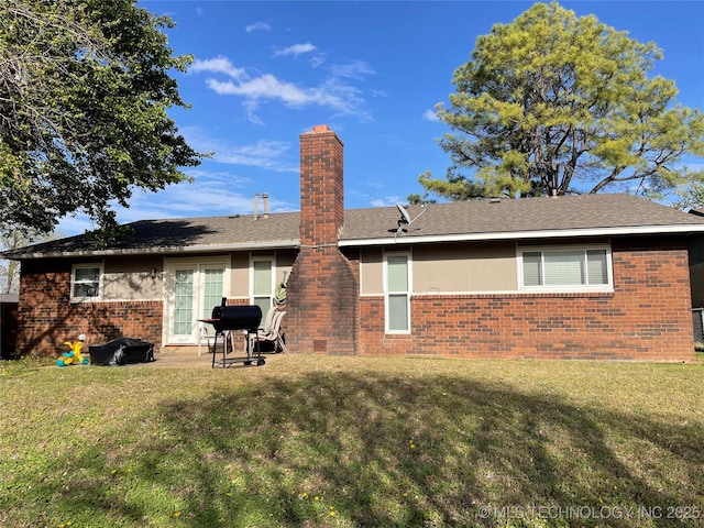 back of house featuring a patio, a chimney, a lawn, and brick siding