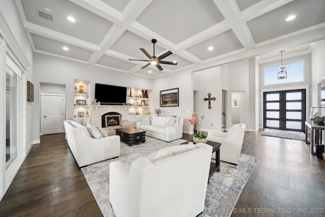 living area with coffered ceiling, a warm lit fireplace, visible vents, and dark wood finished floors