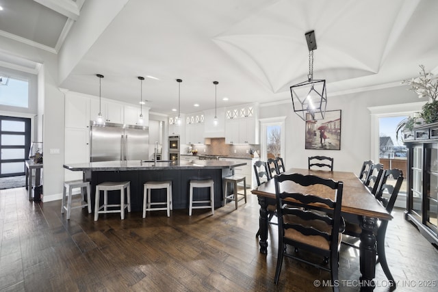 dining space with baseboards, dark wood finished floors, and crown molding