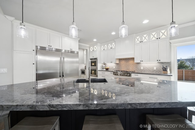 kitchen with backsplash, appliances with stainless steel finishes, glass insert cabinets, white cabinets, and a kitchen breakfast bar