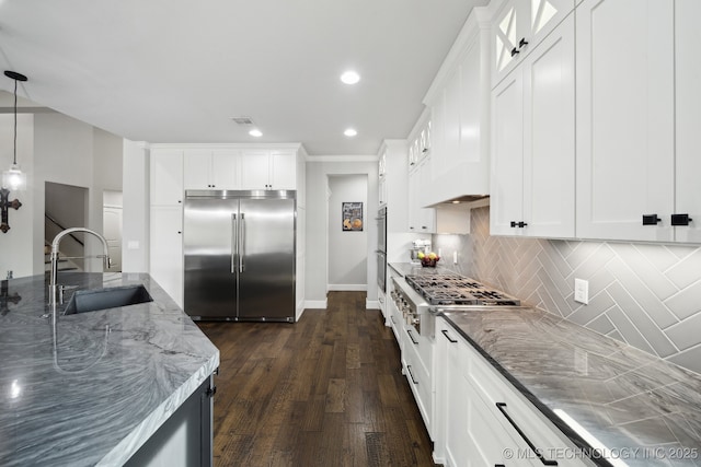 kitchen featuring stainless steel appliances, backsplash, a sink, and light stone countertops