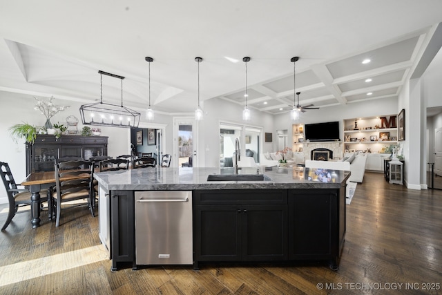 kitchen with dark wood-type flooring, a kitchen island with sink, a sink, a stone fireplace, and coffered ceiling