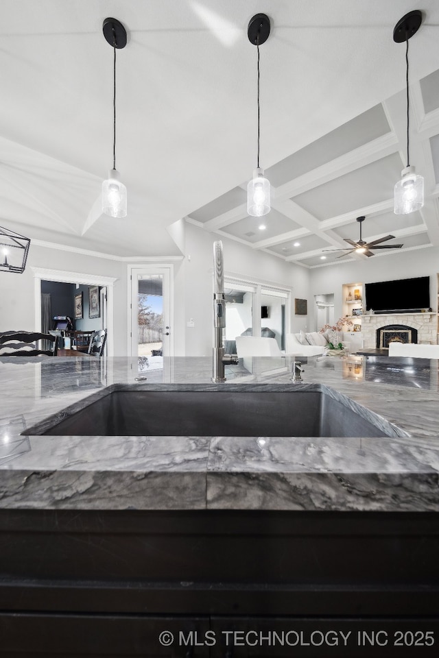 kitchen featuring coffered ceiling, a ceiling fan, open floor plan, dark stone countertops, and beam ceiling