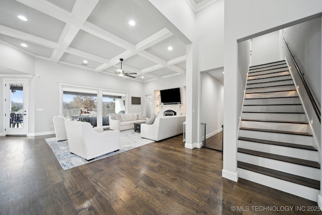 living area featuring ceiling fan, coffered ceiling, baseboards, stairway, and dark wood finished floors