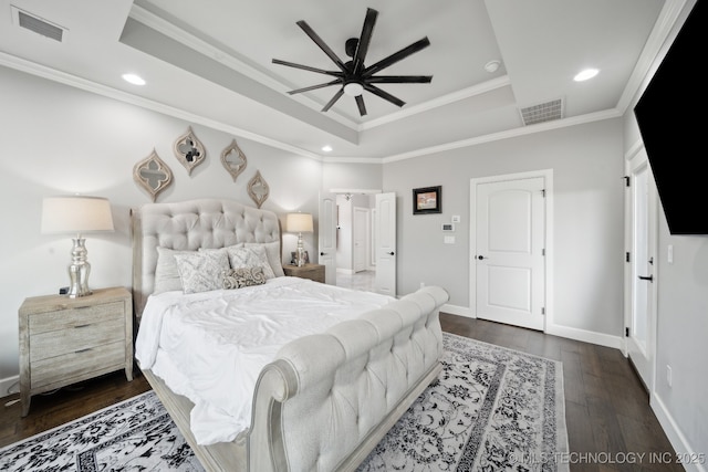 bedroom featuring a tray ceiling, wood-type flooring, visible vents, and crown molding