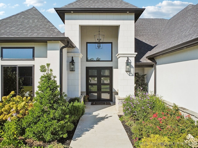 view of exterior entry with french doors and roof with shingles