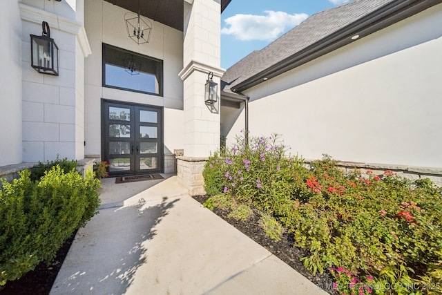 property entrance featuring a shingled roof, french doors, and stucco siding