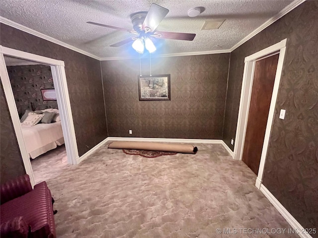 unfurnished room with a textured ceiling, wallpapered walls, carpet, and crown molding