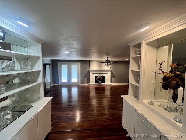 living room with ceiling fan, baseboards, a fireplace with raised hearth, and dark wood-style flooring