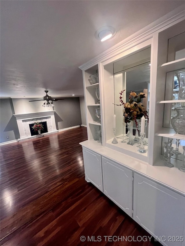 bar with ceiling fan, a fireplace, baseboards, and dark wood finished floors