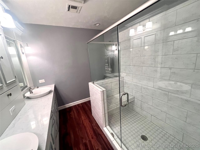 bathroom featuring baseboards, a shower stall, vanity, and wood finished floors