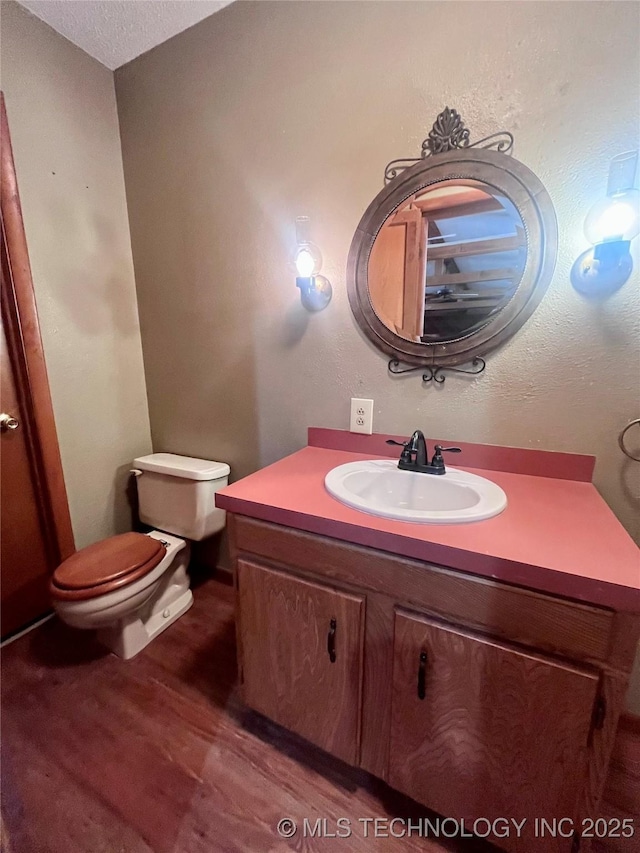 bathroom with toilet, wood finished floors, and vanity