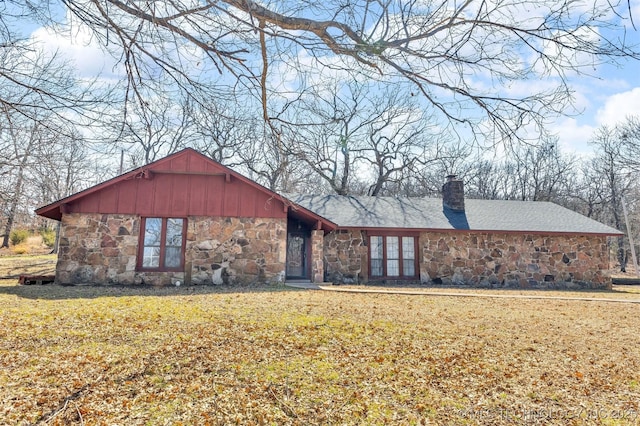 view of front of property with stone siding, a chimney, and a front yard