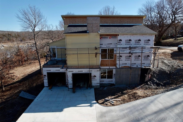 unfinished property featuring driveway, an attached garage, and a shingled roof