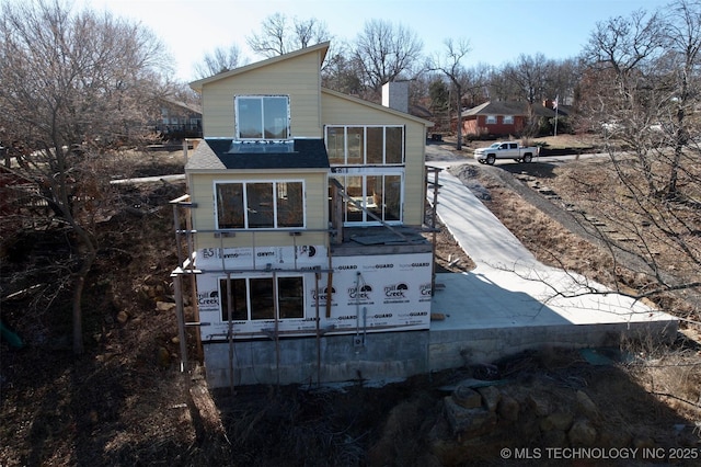 rear view of house with a chimney and a balcony