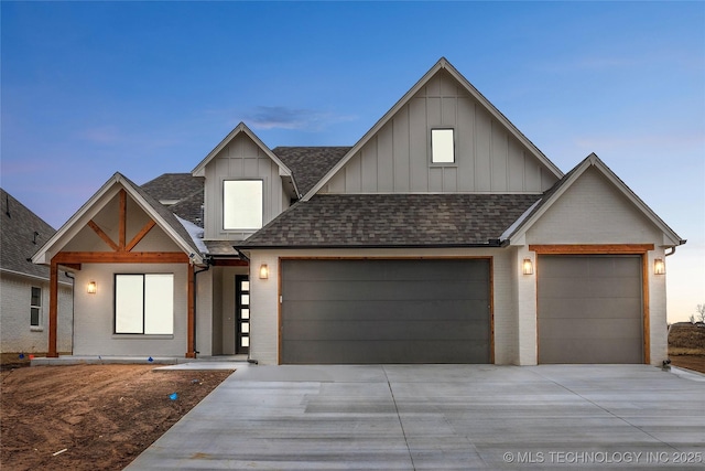 view of front of home with a garage, roof with shingles, brick siding, and board and batten siding