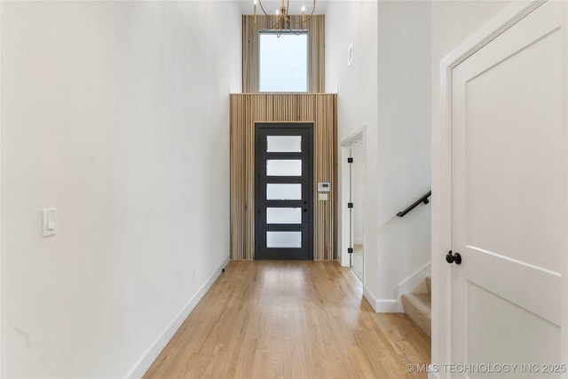 entrance foyer featuring baseboards, light wood finished floors, stairway, and a notable chandelier