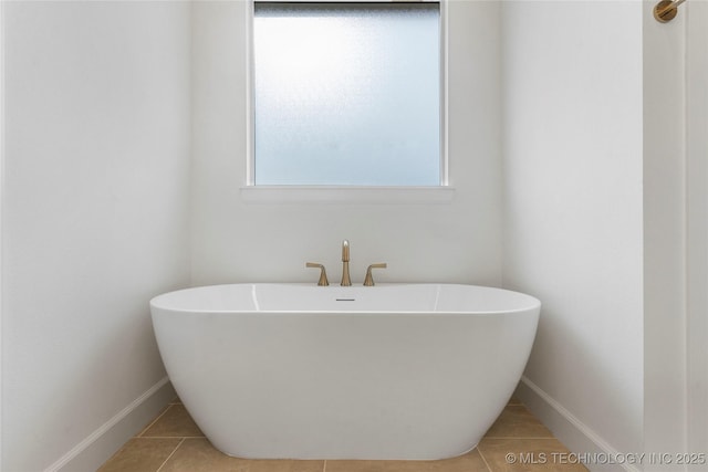 bathroom with a soaking tub, tile patterned flooring, and baseboards