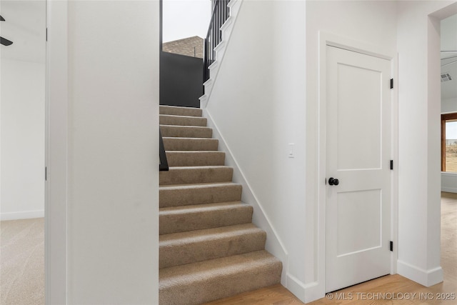 stairway with wood finished floors, visible vents, and baseboards