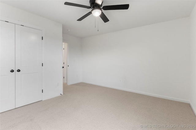 unfurnished bedroom featuring carpet floors, a closet, baseboards, and a ceiling fan