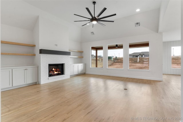 unfurnished living room with light wood-style floors, a fireplace, visible vents, and a wealth of natural light