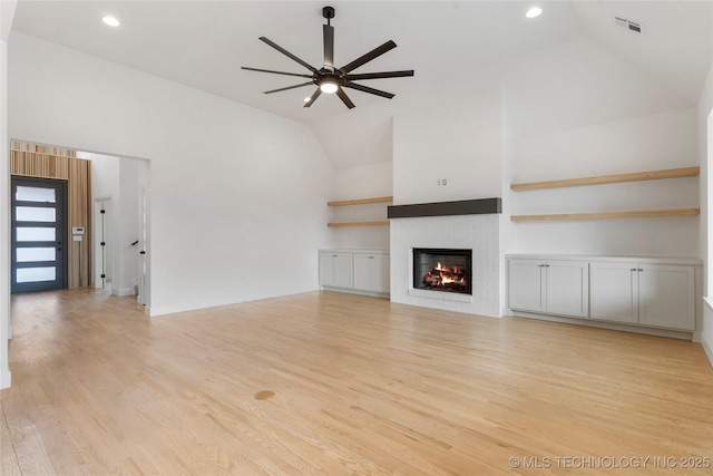 unfurnished living room with a warm lit fireplace, ceiling fan, light wood finished floors, and visible vents