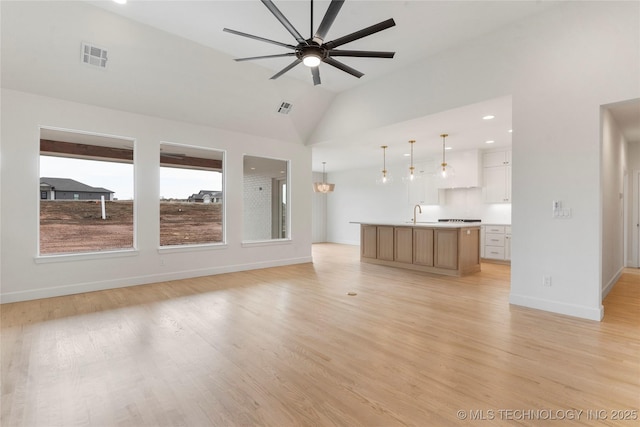 unfurnished living room featuring baseboards, visible vents, a ceiling fan, lofted ceiling, and light wood-style flooring