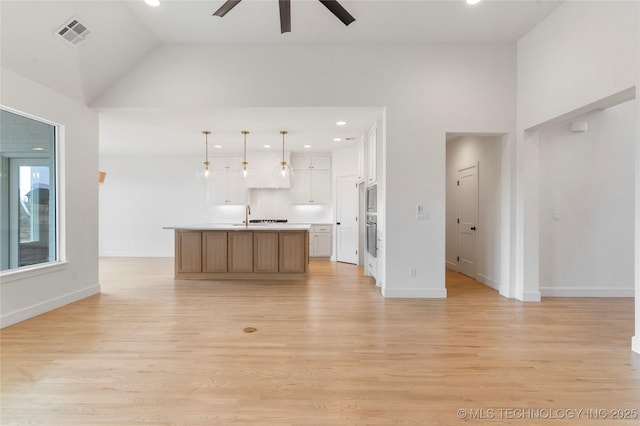 kitchen featuring light wood finished floors, white cabinetry, visible vents, and open floor plan