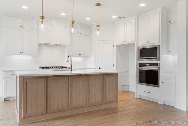 kitchen with light wood-style floors, white cabinetry, stainless steel appliances, and light countertops