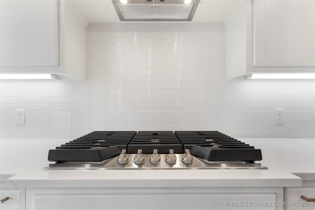 interior details featuring extractor fan, stainless steel gas cooktop, white cabinets, light countertops, and tasteful backsplash