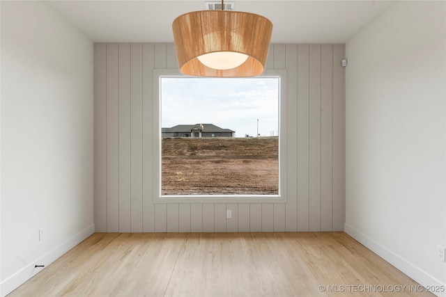 spare room with visible vents, baseboards, and wood finished floors