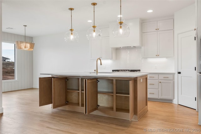 kitchen featuring white cabinetry, a sink, light wood-style flooring, and decorative backsplash