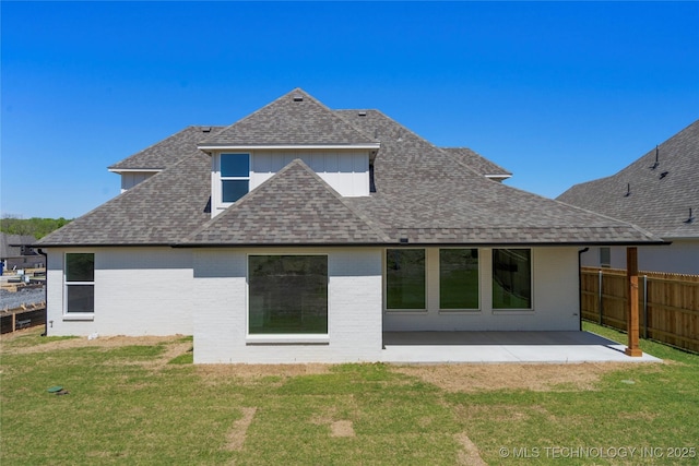 rear view of house featuring fence, a patio area, brick siding, a lawn, and roof with shingles