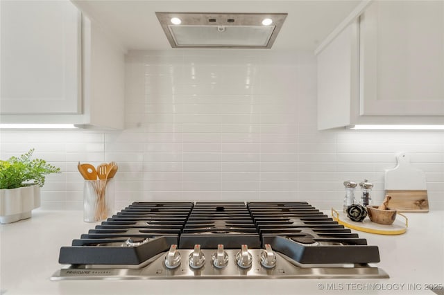 interior details featuring stainless steel gas cooktop, decorative backsplash, white cabinets, and light countertops