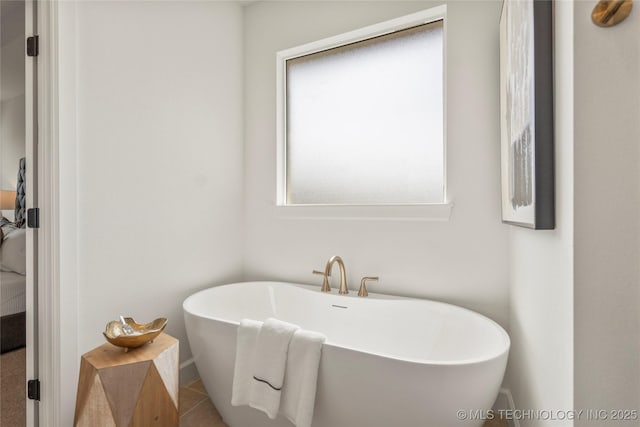 bathroom with a soaking tub, ensuite bath, tile patterned flooring, and baseboards