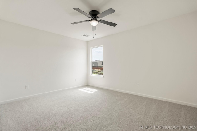 carpeted spare room featuring baseboards, visible vents, and ceiling fan