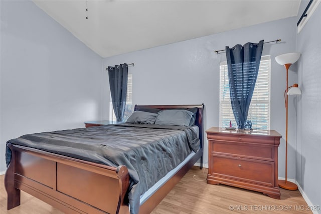 bedroom featuring light wood-style floors, lofted ceiling, and baseboards