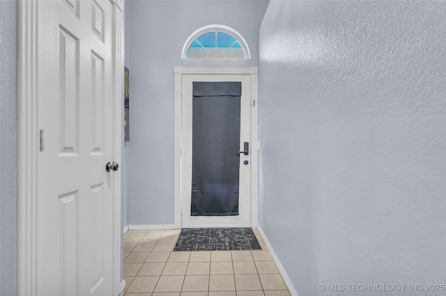 doorway to outside featuring light tile patterned floors and baseboards