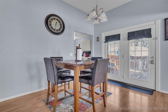 dining area with a chandelier, wood finished floors, and baseboards