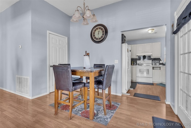 dining space with light wood-style floors, baseboards, and visible vents