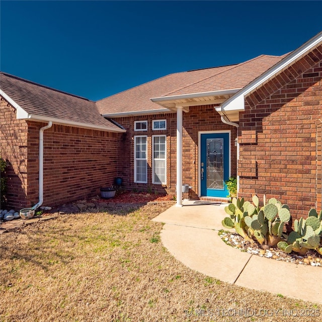 property entrance with brick siding and roof with shingles