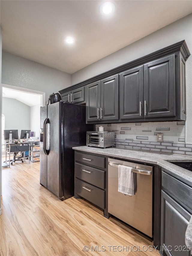 kitchen with light wood finished floors, a toaster, decorative backsplash, dishwasher, and black fridge