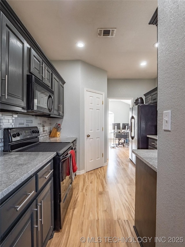 kitchen with visible vents, black appliances, light countertops, light wood-type flooring, and backsplash