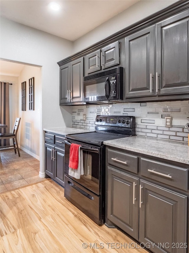 kitchen with decorative backsplash, black appliances, light wood-type flooring, and baseboards