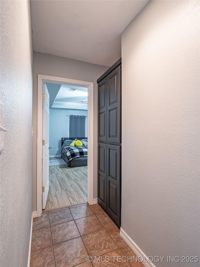 corridor with baseboards and tile patterned flooring