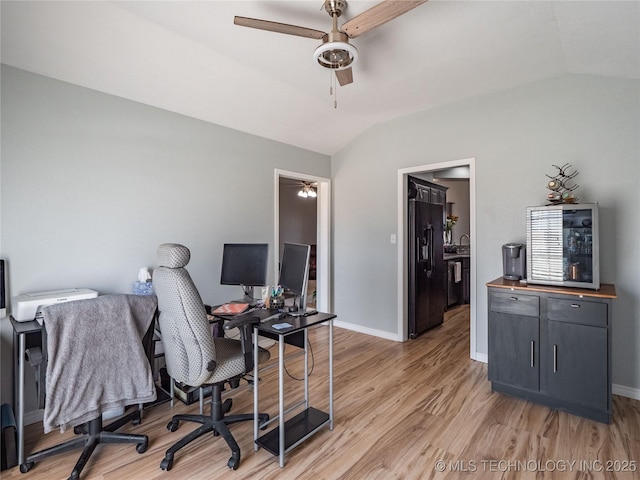 home office with lofted ceiling, a ceiling fan, light wood-type flooring, and baseboards