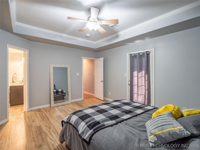 bedroom with baseboards, visible vents, light wood finished floors, crown molding, and a raised ceiling