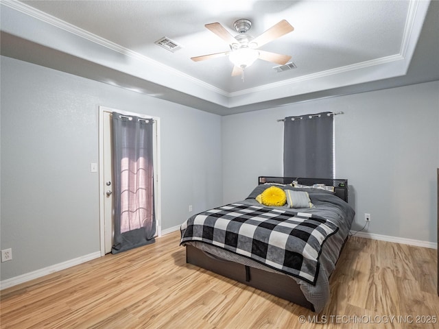 bedroom featuring a tray ceiling, visible vents, and wood finished floors