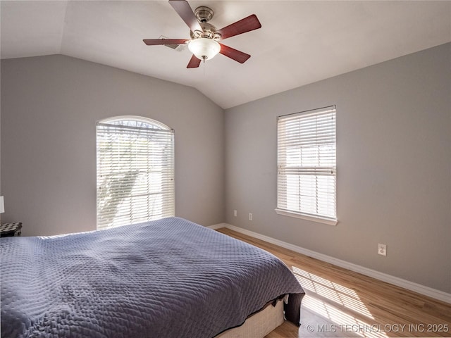 bedroom with baseboards, a ceiling fan, light wood-style floors, and vaulted ceiling